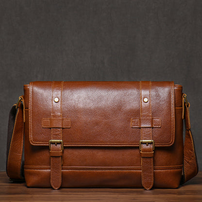Vintage brown leather messenger bag, front view with buckle details, rustic background