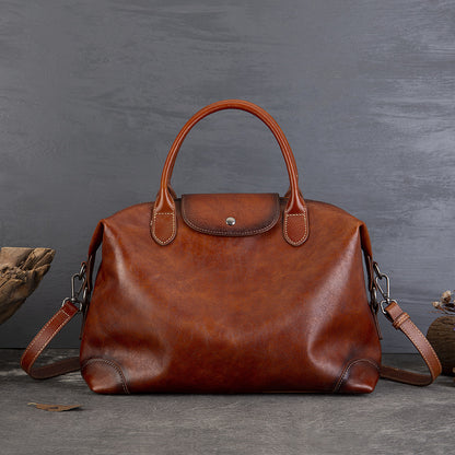 Brown leather handbag with top handles, showcased on a textured gray background, highlighting vintage style