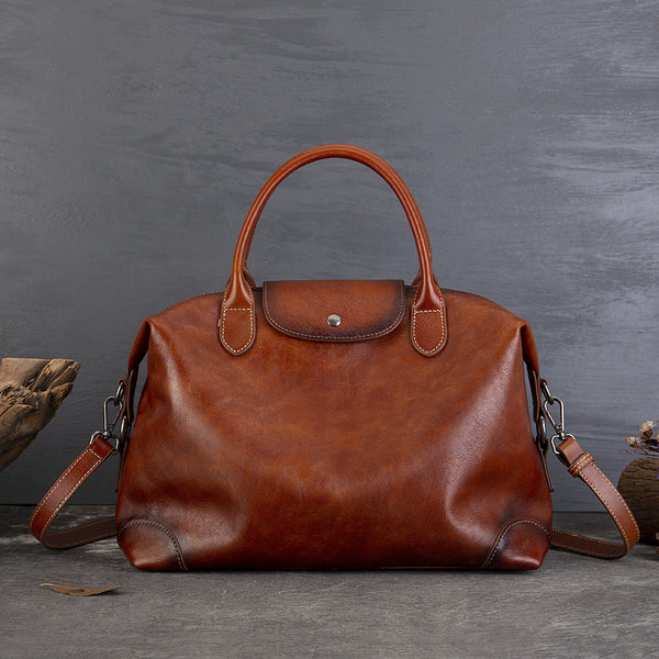 Brown leather handbag with top handles, showcased on a textured gray background, highlighting vintage style