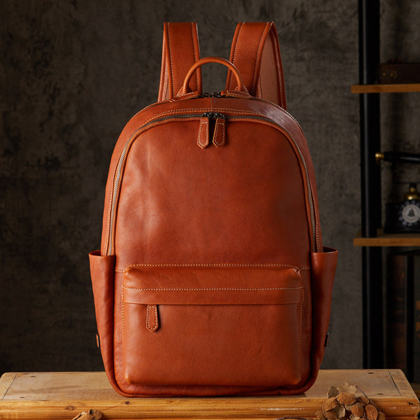 Brown leather backpack, classic design, front view with multiple pockets, on wooden table
