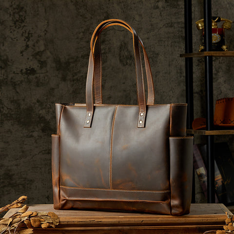 Vintage brown leather tote bag, front view with dual handles, rustic background
