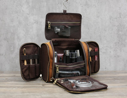 Brown leather toiletry bag, fully open with multiple compartments, filled with grooming products and tools