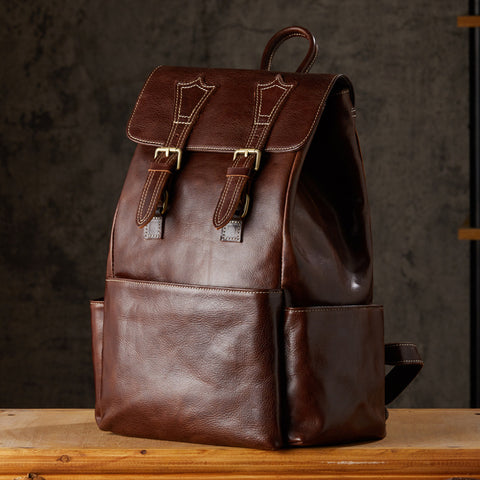 Brown leather backpack, front view with buckle closures, rustic background