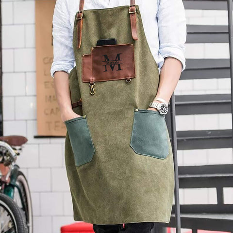 Person wearing olive green canvas apron with brown leather "M Michale" pocket